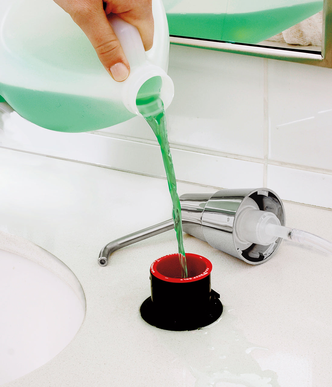 A hand pouring foam green soap into the Bobrick B-8236 foam soap dispenser.
